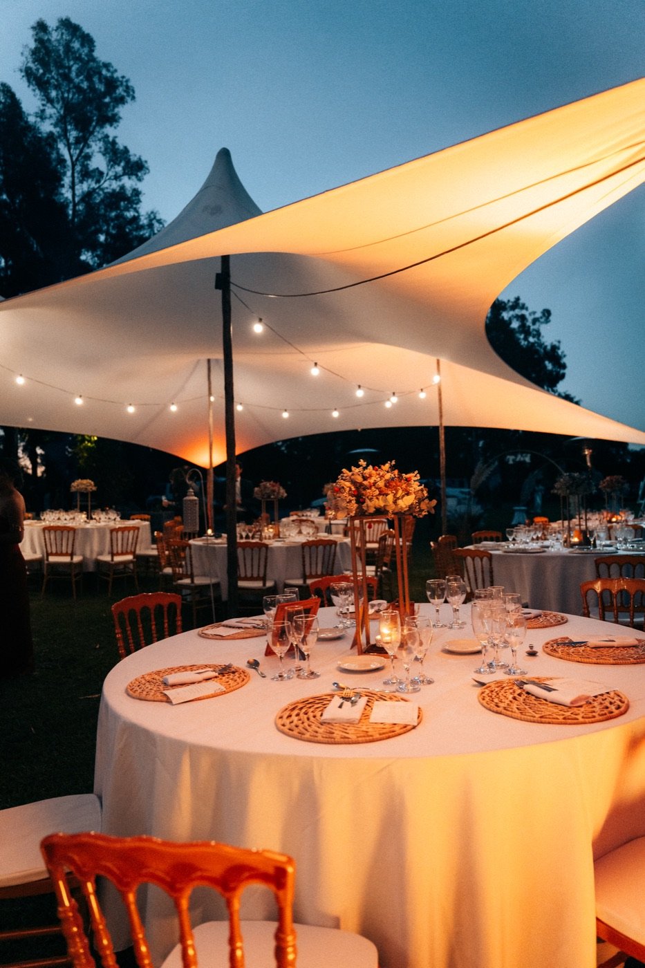 Carpa con mesas vestidas para una boda al atardecer